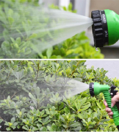 Flexible garden hose spray nozzle watering green plants with mist and jet spray modes.