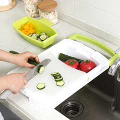 Kitchen plastic chopping board with silicone drainage basin, cutting cucumbers and tomatoes over kitchen sink.