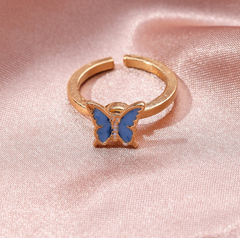 Gold Fidget Spinner Rotatable Ring for Women with blue butterfly design on pink fabric background