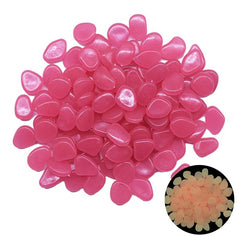 Pink glow in the dark garden pebbles made from photoluminescent resin, glowing softly in darkness.