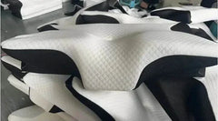 Stack of white and black ergonomic memory foam cervical pillows with quilted texture promoting neck support and sleep comfort