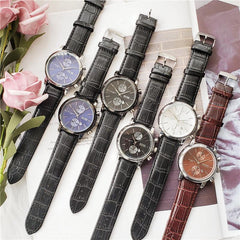 Collection of men's quartz high quality watches with leather straps and metal cases in various dial colors displayed on a magazine page with pink flowers nearby