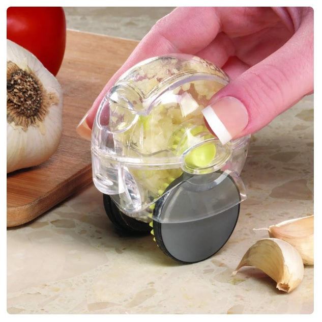 Transparent Rolling Garlic Chopper with black wheels mincing garlic cloves on kitchen counter