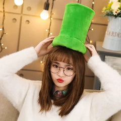 Young woman wearing glasses and a white sweater holding a plush green mushroom hat on her head in a cozy indoor setting