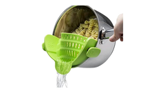Green silicone pot strainer clipped on a saucepan draining water from cooked pasta