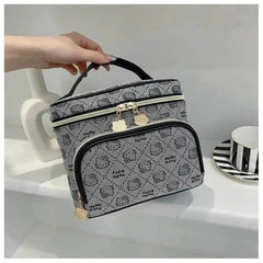 Gray Hello Kitty makeup bag with black handle and gold zipper pulls featuring Hello Kitty faces and text pattern