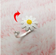 Fidget Spinner Rotatable Ring for women with a silver flower design and smooth spinning center on a soft pink background.