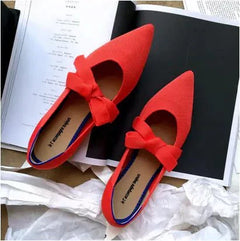 Red flat casual boat shoes with bow and pointed Mary Jane style on magazine background