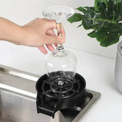 Hand using High Pressure Cup Washer to rinse an upside-down wine glass on a kitchen sink setup