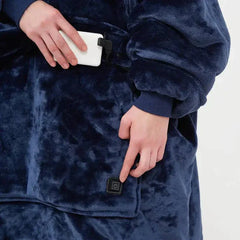 Person adjusting USB-powered heated hoodie blanket with plush fleece fabric and power button on front pocket in navy blue color