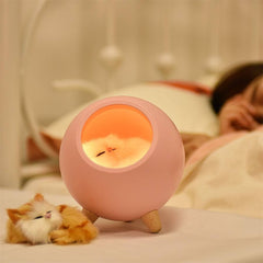 LED Cat Light with warm yellow glow in pink spherical design on wooden legs emitting cozy ambient light
