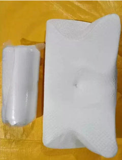 White memory foam cervical pillow with ergonomic neck support and breathable cover on yellow surface next to wrapped packaging