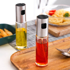Kitchen condiment bottles with stainless steel spray heads filled with oil and vinegar on a kitchen countertop.