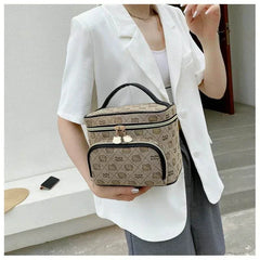 Compact Hello Kitty makeup bag with beige pattern and black trim, held by person in white blazer.