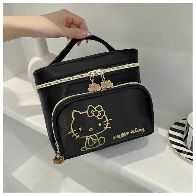 Black Hello Kitty makeup bag with gold character design and zipper closures held by a hand