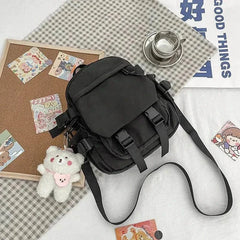 Black Korean Nylon Oxford Fabric Versatile Literature Backpack with bear pendant and adjustable strap on checkered cloth background