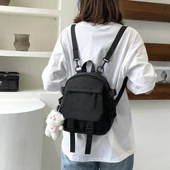 Black Korean Nylon Oxford Fabric Versatile Literature Backpack with bear pendant worn on back of person in white shirt