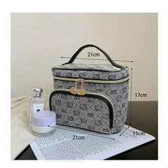 Hello Kitty makeup bag with handle, gray patterned design, multiple compartments, and gold zipper charms, measuring 21cm by 17cm by 15cm.