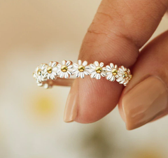 Close-up of a women's metal fidget spinner rotatable ring with a daisy flower design held between fingers