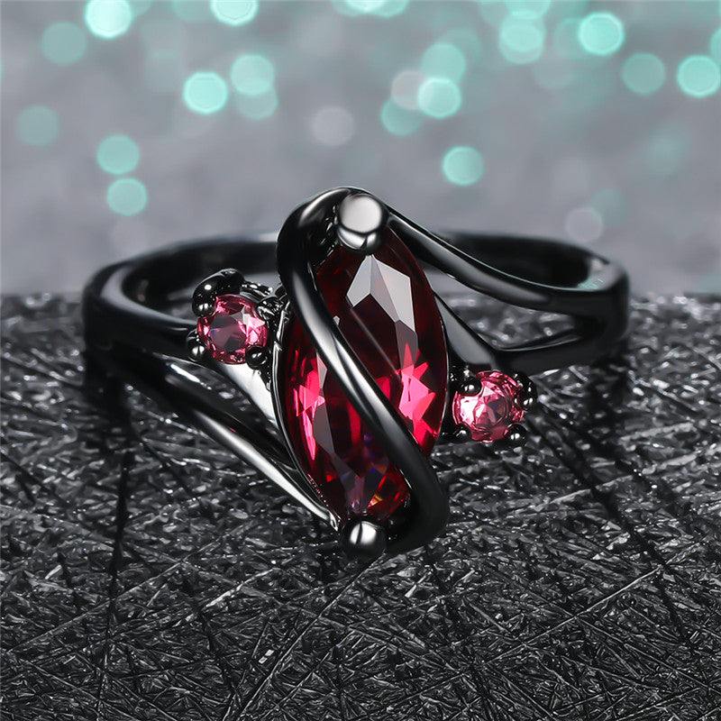 Elegant crystal ring with a large red leaf-shaped center stone and sparkling white crystals on a 14K black gold band