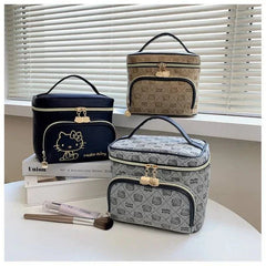 Set of three Hello Kitty makeup bags in black, beige, and gray with gold zippers and handles on a white surface near window blinds.